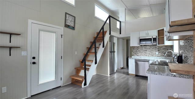 kitchen with dark wood finished floors, white cabinetry, decorative backsplash, and stainless steel appliances