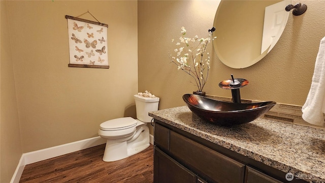 bathroom with baseboards, wood finished floors, toilet, and vanity