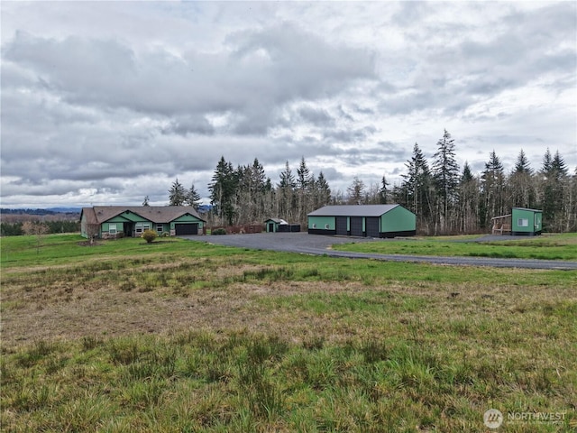 view of yard with a detached garage and a rural view