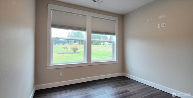 unfurnished room featuring dark wood-style flooring, baseboards, and visible vents