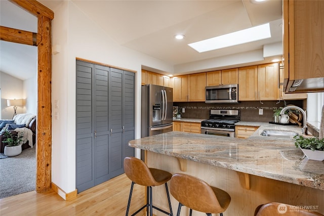 2932 Huntington St, Bellingham, WA 98226 - kitchen with light stone counters, a peninsula, backsplash, appliances with stainless steel finishes, and a sink