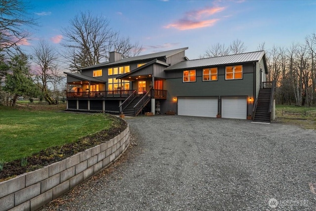 view of front of home featuring a chimney, a garage, stairway, driveway, and a yard