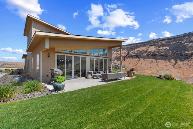 rear view of property with a yard, a patio, outdoor lounge area, and a mountain view