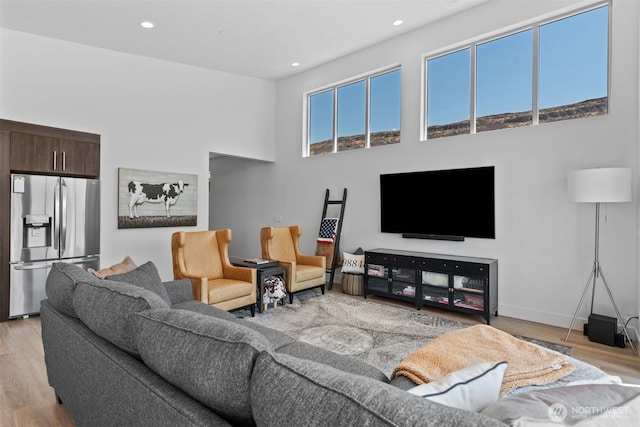 living area featuring wood finished floors, a high ceiling, and recessed lighting