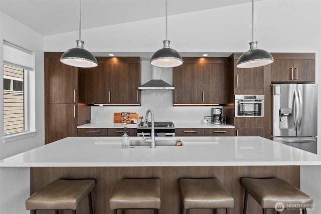 kitchen with light countertops, wall chimney range hood, vaulted ceiling, and stainless steel appliances