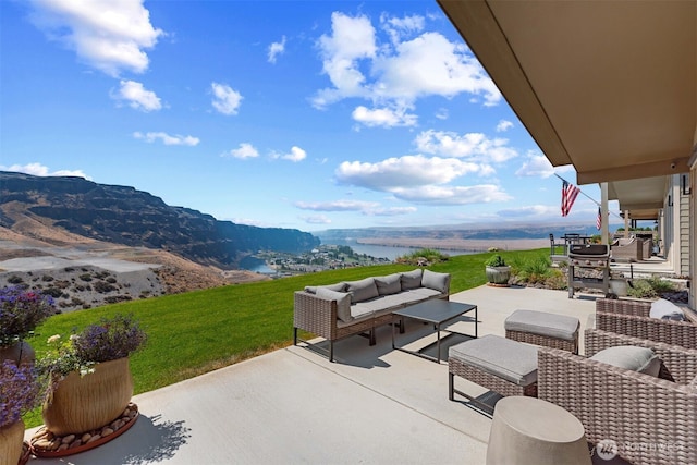 view of patio with an outdoor living space and a water and mountain view