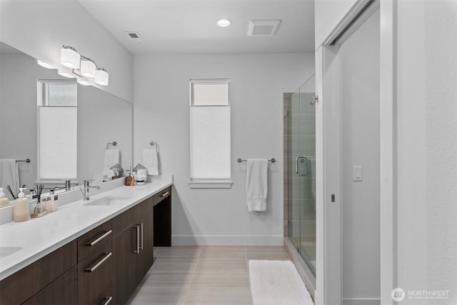 bathroom featuring a shower stall, double vanity, a sink, and visible vents