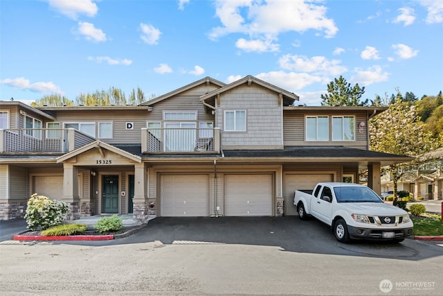 view of property featuring an attached garage, a balcony, and driveway