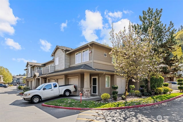 view of front of house with an attached garage, driveway, and stone siding