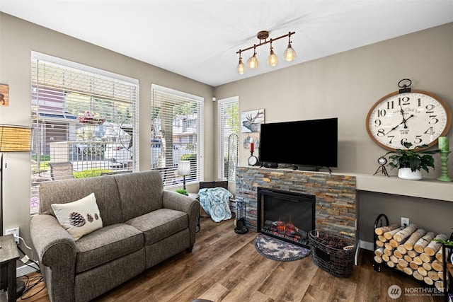 living room with a stone fireplace and wood finished floors
