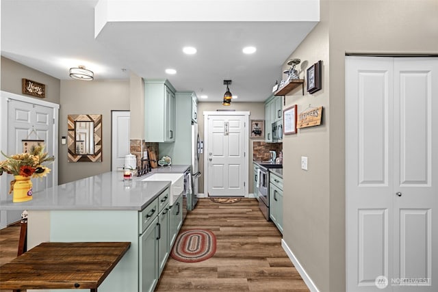kitchen with a peninsula, dark wood finished floors, recessed lighting, decorative backsplash, and appliances with stainless steel finishes
