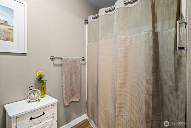 full bathroom featuring a shower with curtain, baseboards, and wood finished floors