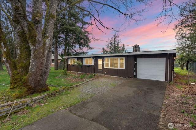 view of front of house with board and batten siding, a garage, aphalt driveway, and a chimney