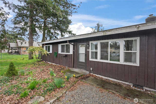 view of front facade with board and batten siding, a front yard, and a chimney