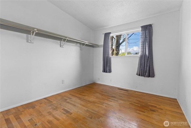 interior space featuring visible vents, light wood-style floors, and lofted ceiling