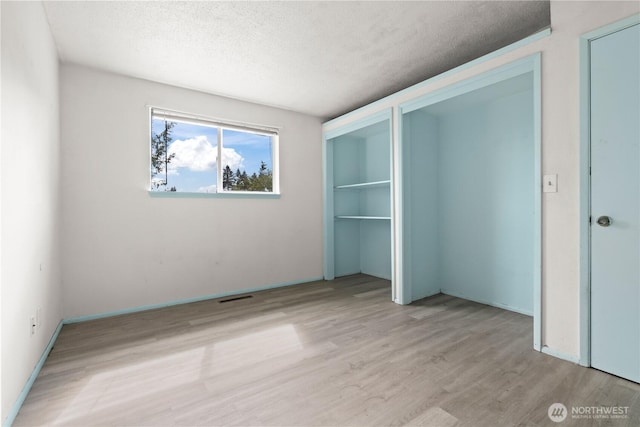 unfurnished bedroom featuring visible vents, a textured ceiling, and wood finished floors