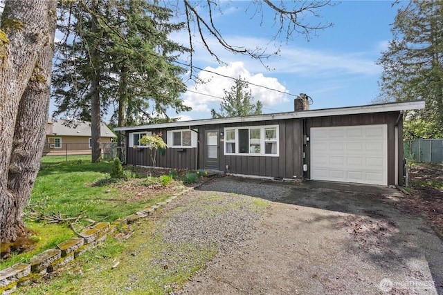 ranch-style home featuring driveway, a chimney, fence, an attached garage, and board and batten siding