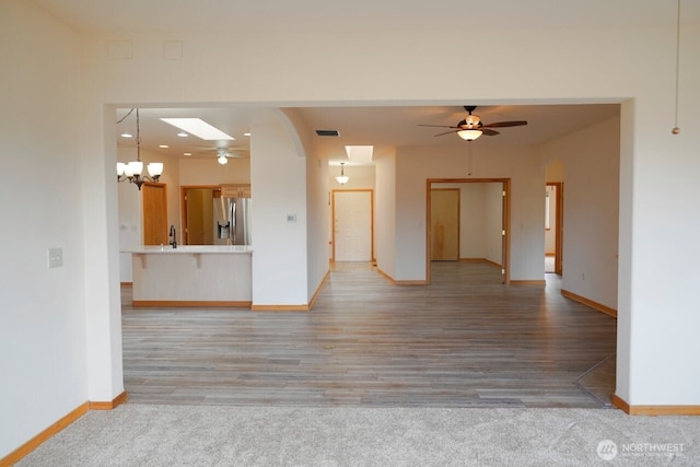 230 Choice Loop, Sequim, WA 98382 - unfurnished living room featuring a ceiling fan, a chandelier, light wood-type flooring, and arched walkways
