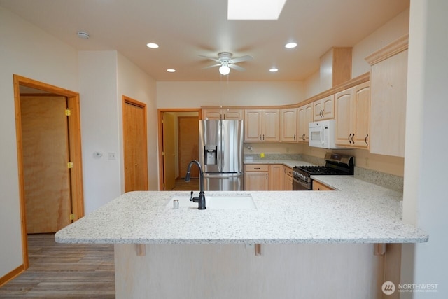 230 Choice Loop, Sequim, WA 98382 - kitchen featuring stainless steel appliances, light brown cabinets, a peninsula, light stone counters, and a skylight