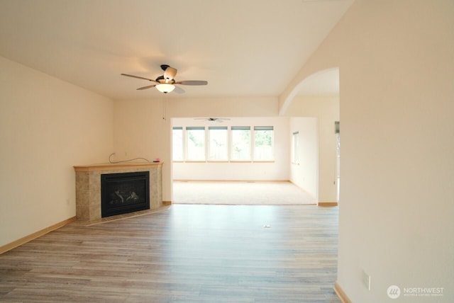 230 Choice Loop, Sequim, WA 98382 - unfurnished living room featuring ceiling fan, wood finished floors, a tile fireplace, and arched walkways