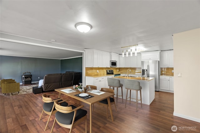dining space featuring baseboards, a wood stove, and dark wood-type flooring