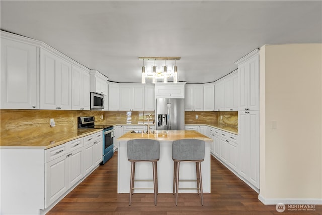 kitchen with white cabinets, stainless steel appliances, dark wood-type flooring, and an island with sink