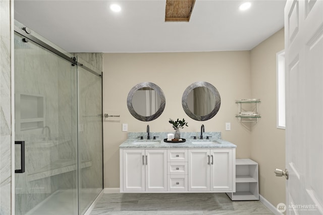 bathroom featuring double vanity, baseboards, a sink, and a marble finish shower