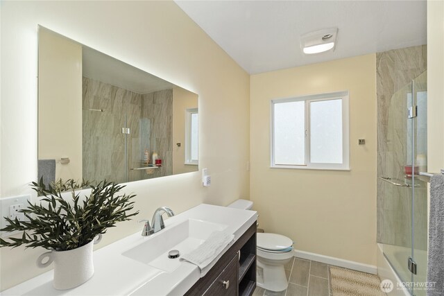 bathroom featuring vanity, toilet, baseboards, tile patterned floors, and enclosed tub / shower combo