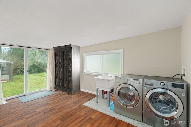 clothes washing area featuring laundry area, wood finished floors, separate washer and dryer, and plenty of natural light