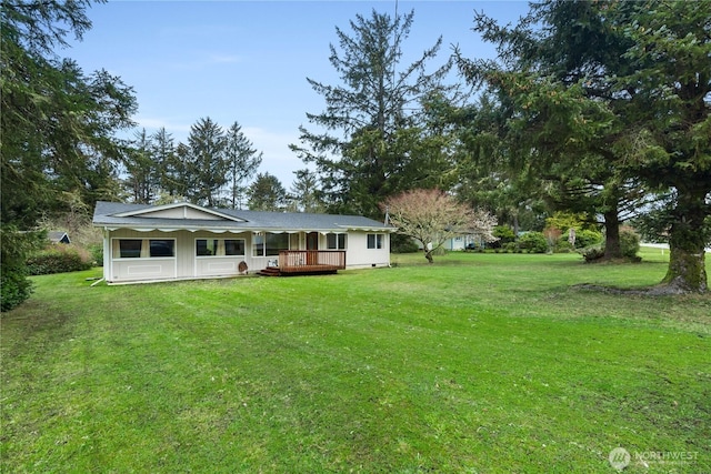 rear view of property featuring a lawn and a wooden deck