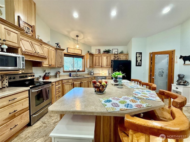 kitchen featuring light countertops, a sink, a kitchen island, a breakfast bar area, and stainless steel appliances