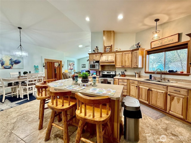 kitchen with light countertops, appliances with stainless steel finishes, a sink, pendant lighting, and a center island