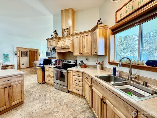 kitchen featuring light countertops, a high ceiling, a sink, light brown cabinets, and appliances with stainless steel finishes