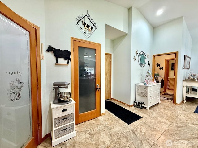 corridor with a towering ceiling and baseboards