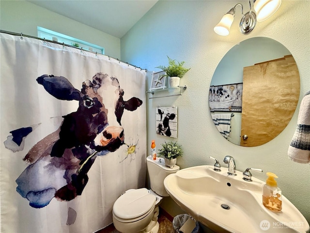 full bath featuring a shower with curtain, toilet, a sink, and a textured wall
