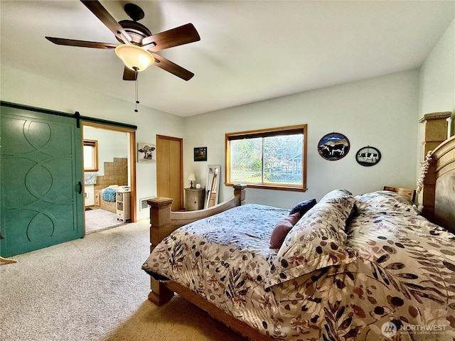 carpeted bedroom featuring a ceiling fan, ensuite bath, and a barn door