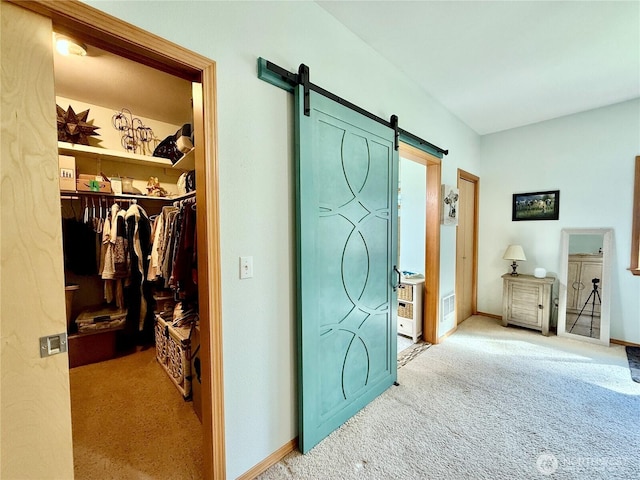 carpeted bedroom featuring baseboards, a barn door, a closet, and a spacious closet