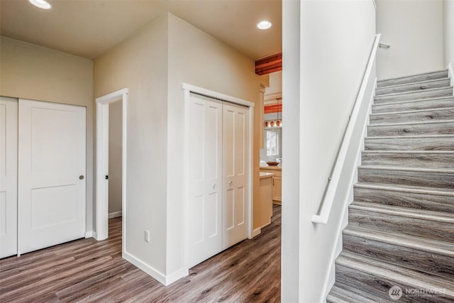 stairway with baseboards, wood finished floors, and recessed lighting