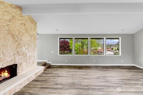 2210 Martin Rd, Mount Vernon, WA 98273 - unfurnished living room featuring wood finished floors, a stone fireplace, and baseboards