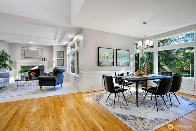 17955 SE 60th St, Bellevue, WA 98006 - dining space with a wainscoted wall, a notable chandelier, a high end fireplace, a decorative wall, and light wood-style floors