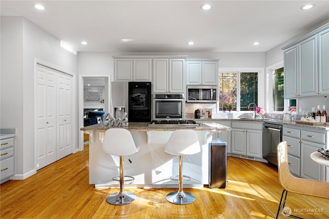17955 SE 60th St, Bellevue, WA 98006 - kitchen with a kitchen bar, recessed lighting, a sink, light wood finished floors, and appliances with stainless steel finishes