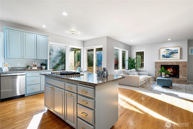 17955 SE 60th St, Bellevue, WA 98006 - kitchen featuring a tiled fireplace, a kitchen island, appliances with stainless steel finishes, light wood-style floors, and recessed lighting