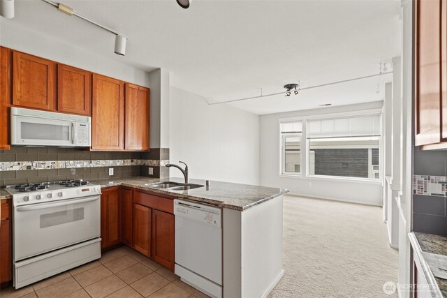 109 2nd St S Unit 337, Kirkland, WA 98033 - kitchen with white appliances, a peninsula, a sink, brown cabinets, and decorative backsplash