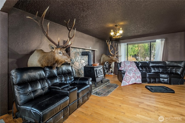 192 Meade Hill Rd, Glenoma, WA 98336 - living room with a textured ceiling, an inviting chandelier, a wood stove, and hardwood / wood-style floors