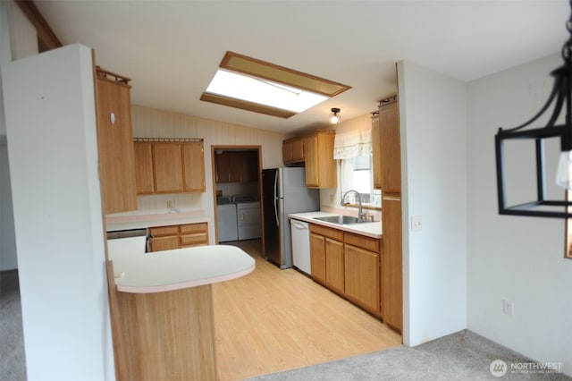 1415 84th St SE Unit 136, Everett, WA 98208 - kitchen with light countertops, lofted ceiling with skylight, independent washer and dryer, a sink, and white dishwasher