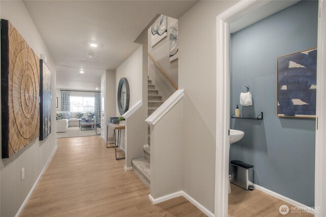 hallway with baseboards, wood finished floors, and stairway