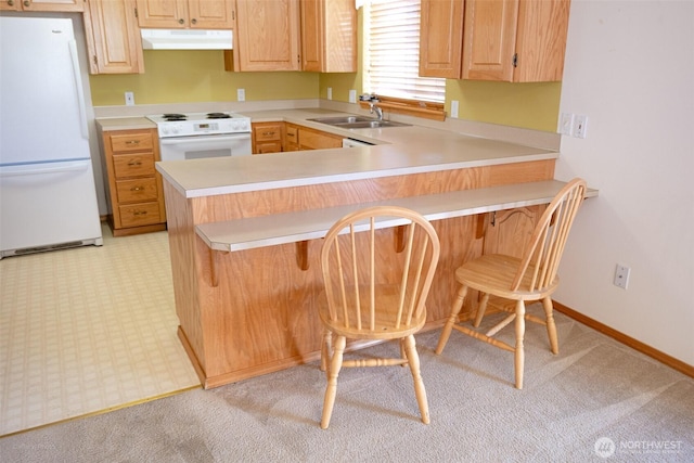 kitchen featuring a sink, light countertops, white appliances, a peninsula, and extractor fan