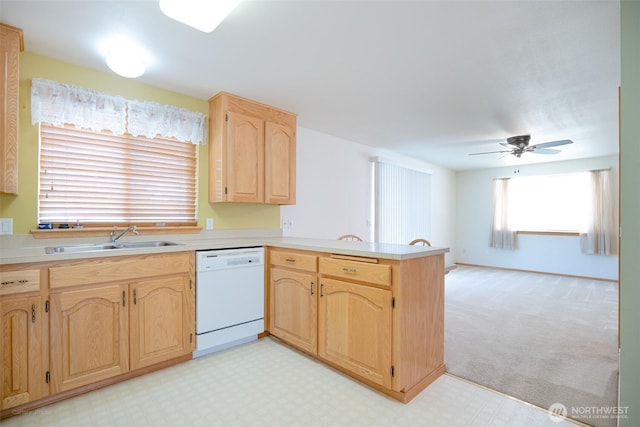 kitchen with white dishwasher, light brown cabinets, a sink, a peninsula, and light floors