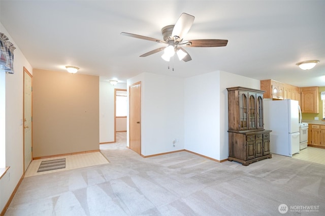 unfurnished living room with light carpet, ceiling fan, and baseboards