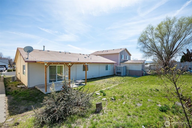 rear view of property featuring a patio area, central AC unit, fence, and a lawn